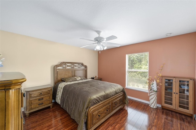 bedroom featuring baseboards, dark wood finished floors, and a ceiling fan