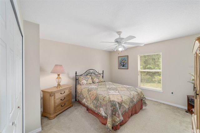 bedroom with light carpet, baseboards, a ceiling fan, and a closet