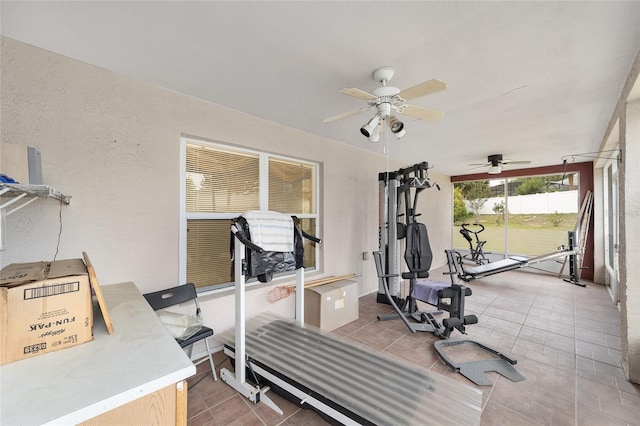 workout area featuring ceiling fan and a textured wall