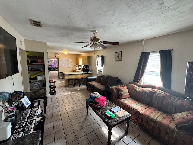 living room featuring tile patterned floors, ceiling fan, and a textured ceiling