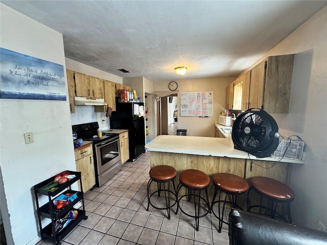 kitchen with stainless steel electric range oven, under cabinet range hood, freestanding refrigerator, a peninsula, and light countertops