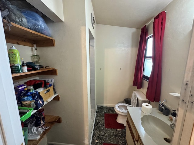 bathroom with vanity, toilet, and baseboards