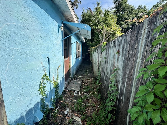 view of side of property with fence and stucco siding
