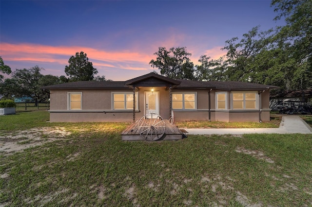 single story home featuring stucco siding and a yard