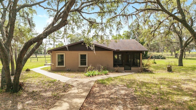 rear view of house with a sunroom and stucco siding