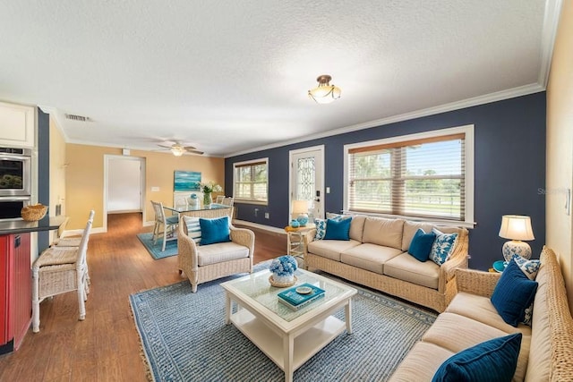 living room featuring crown molding, ceiling fan, wood finished floors, baseboards, and a textured ceiling