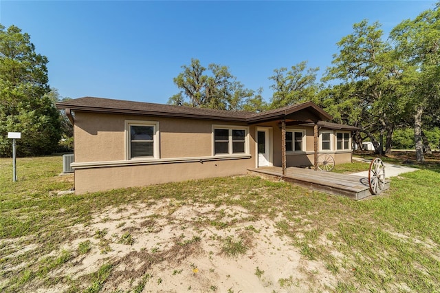 back of property with stucco siding, a deck, a lawn, and cooling unit