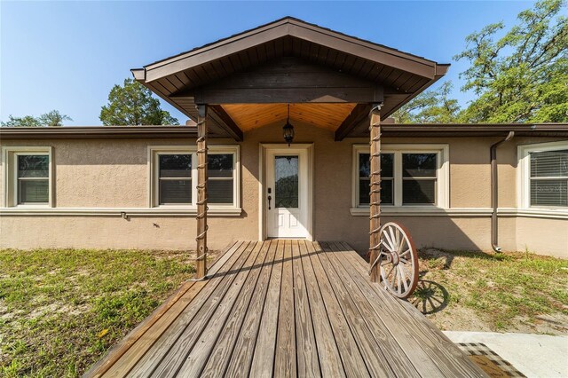 view of exterior entry featuring stucco siding and a deck