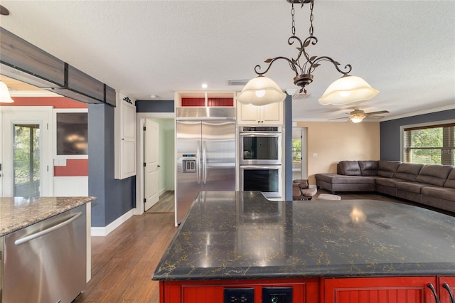 kitchen with appliances with stainless steel finishes, open floor plan, dark wood-style floors, a textured ceiling, and a ceiling fan