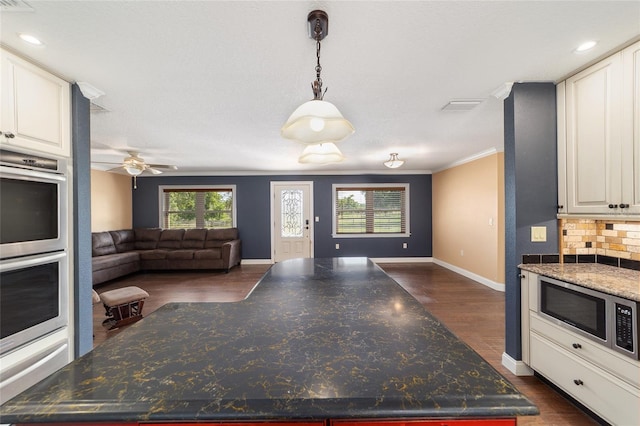 kitchen with stainless steel appliances, open floor plan, a center island, baseboards, and dark wood-style flooring