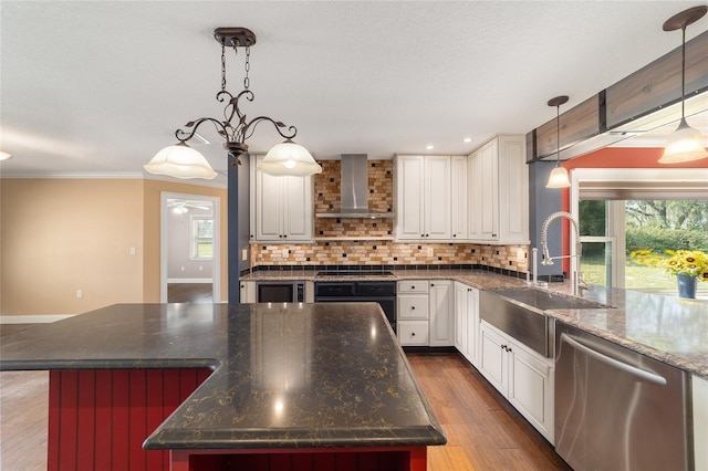 kitchen with wall chimney range hood, stainless steel dishwasher, a sink, wall oven, and tasteful backsplash