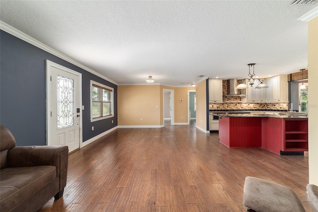 living area with a textured ceiling, crown molding, dark wood finished floors, and baseboards