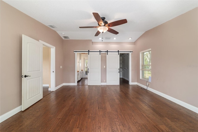unfurnished bedroom featuring baseboards, dark wood-type flooring, vaulted ceiling, a walk in closet, and recessed lighting