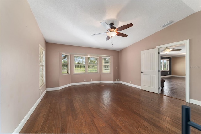 empty room featuring a ceiling fan, vaulted ceiling, wood finished floors, baseboards, and a textured ceiling