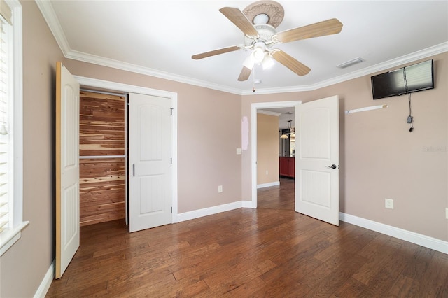unfurnished bedroom featuring wood finished floors, crown molding, baseboards, and ceiling fan