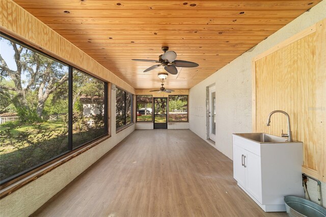 unfurnished sunroom featuring a sink and a ceiling fan