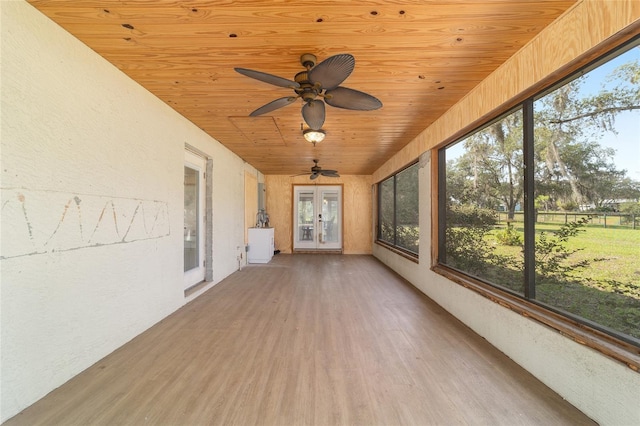 unfurnished sunroom with french doors, wooden ceiling, wood finished floors, and a textured wall