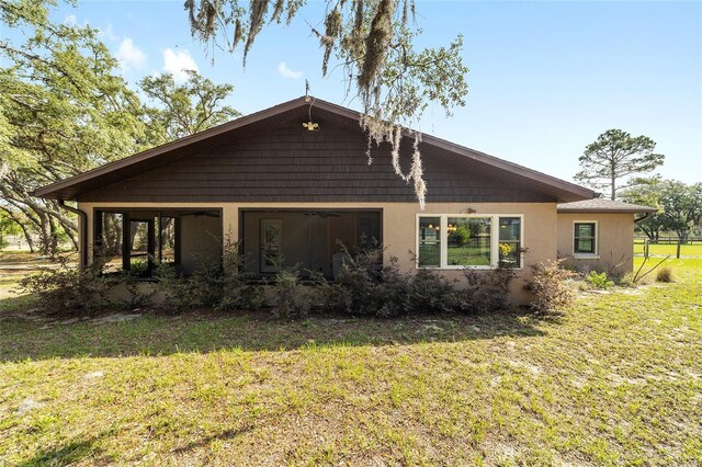 rear view of property featuring a lawn and stucco siding