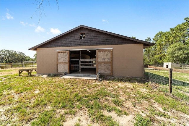 back of property featuring concrete block siding, an outbuilding, an exterior structure, and fence