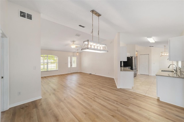 4886 NW 30th Pl, Ocala, FL 34482 - unfurnished living room featuring a sink, vaulted ceiling, light wood finished floors, a ceiling fan, and baseboards