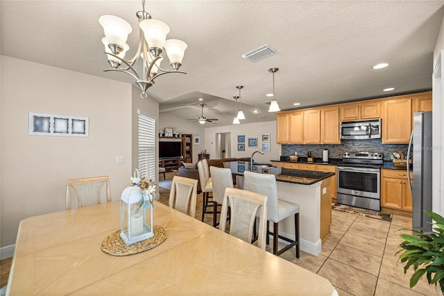 kitchen featuring stainless steel appliances, decorative backsplash, a ceiling fan, a sink, and dark countertops