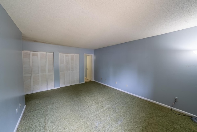 carpeted empty room with a textured ceiling and baseboards