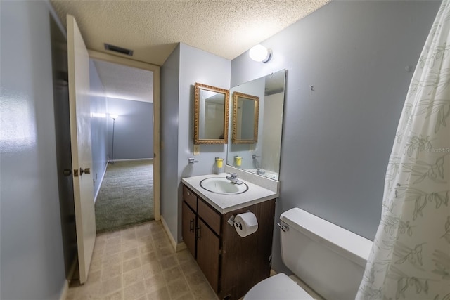 full bath featuring toilet, vanity, a textured ceiling, and baseboards