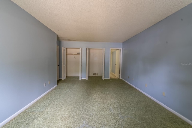 unfurnished bedroom featuring carpet flooring, two closets, baseboards, and a textured ceiling