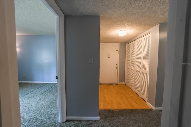 hall with carpet, a textured ceiling, and baseboards