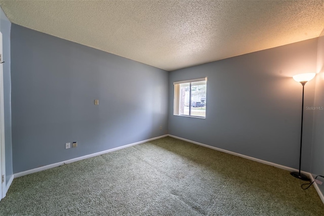 carpeted empty room featuring a textured ceiling and baseboards