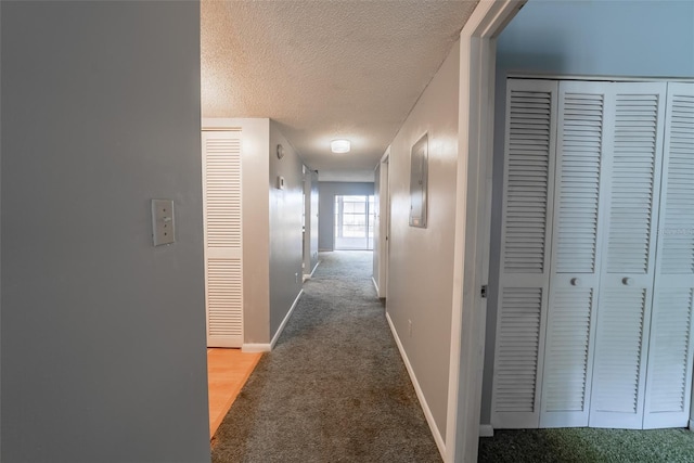 hallway featuring carpet, a textured ceiling, and baseboards