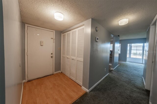 hallway featuring a textured ceiling and baseboards