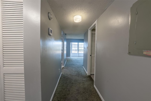 hall featuring carpet, electric panel, a textured ceiling, and baseboards