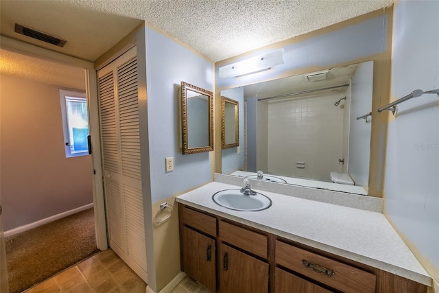 full bath with vanity, a textured ceiling, and a closet