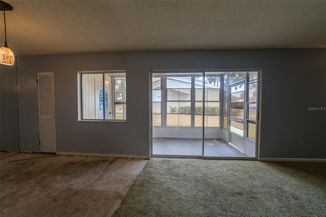 carpeted spare room with a textured ceiling and baseboards