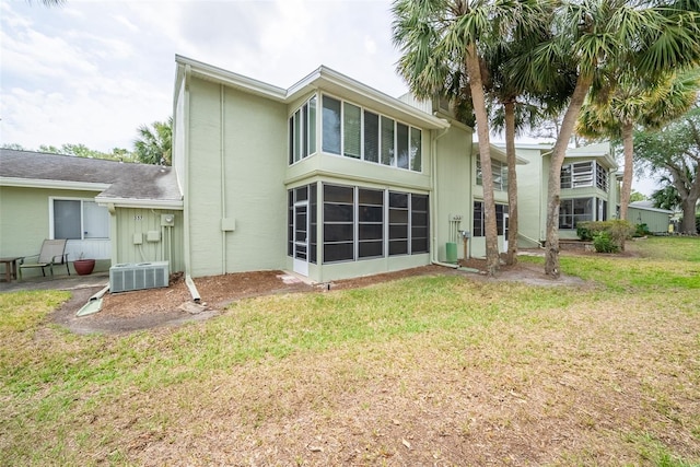 back of property featuring central air condition unit and a lawn