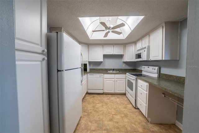 kitchen with white appliances, a ceiling fan, dark countertops, white cabinets, and a textured ceiling