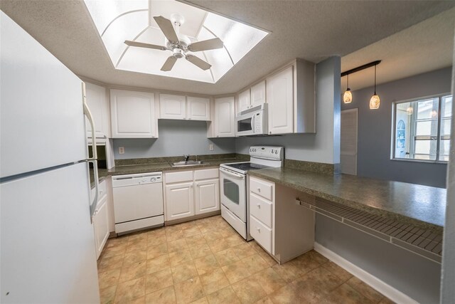 kitchen featuring white appliances, dark countertops, a sink, and white cabinets