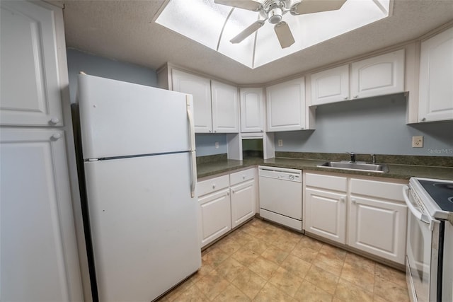 kitchen featuring white appliances, a sink, white cabinets, dark countertops, and ceiling fan