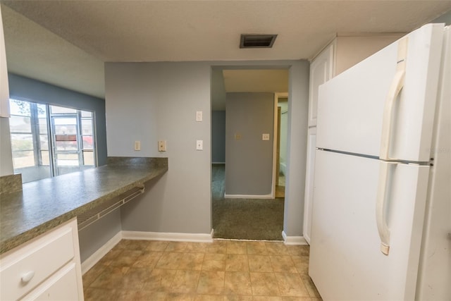 kitchen with freestanding refrigerator, white cabinetry, baseboards, and dark countertops