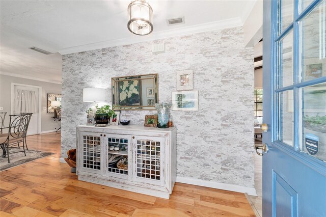 foyer with ornamental molding, wood finished floors, and baseboards
