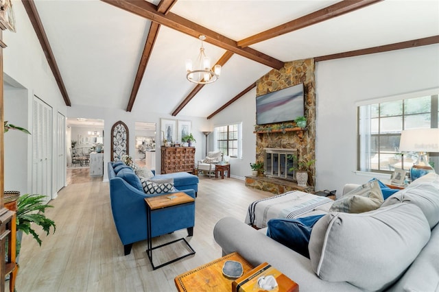 living area with a chandelier, a stone fireplace, and light wood finished floors