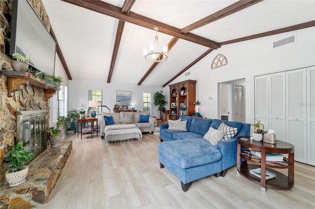 living room featuring a chandelier, light wood-type flooring, beamed ceiling, a stone fireplace, and high vaulted ceiling