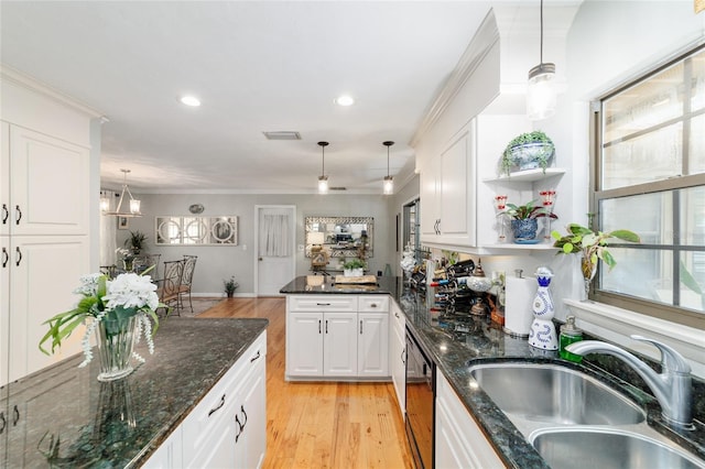 kitchen featuring a sink, light wood finished floors, black dishwasher, white cabinetry, and plenty of natural light