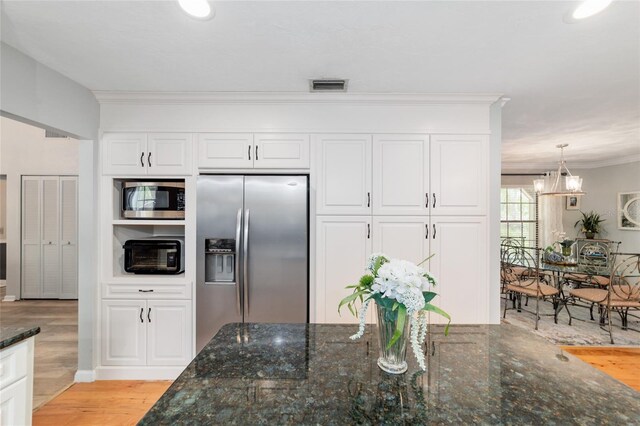 kitchen featuring appliances with stainless steel finishes, ornamental molding, white cabinets, light wood-type flooring, and a chandelier