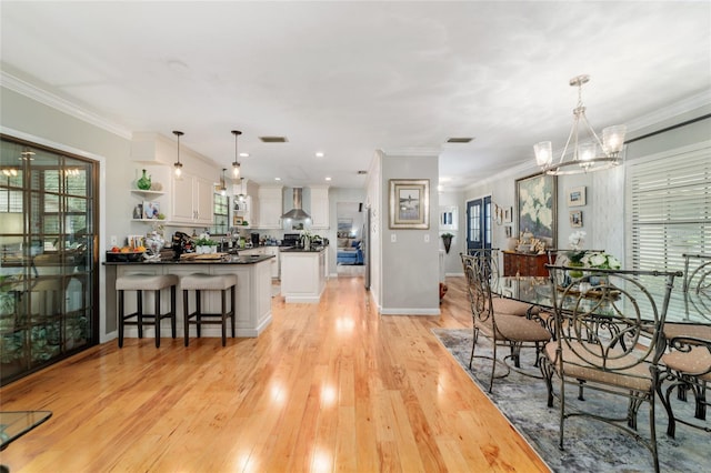 dining area featuring a chandelier, light wood-style flooring, plenty of natural light, ornamental molding, and baseboards
