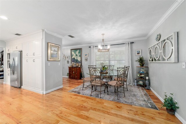 dining area with light wood-style floors, ornamental molding, baseboards, and a chandelier