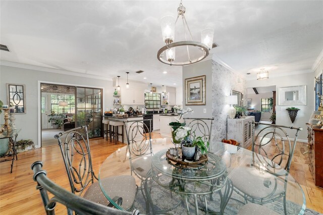 dining room featuring ornamental molding, a chandelier, and light wood-style flooring