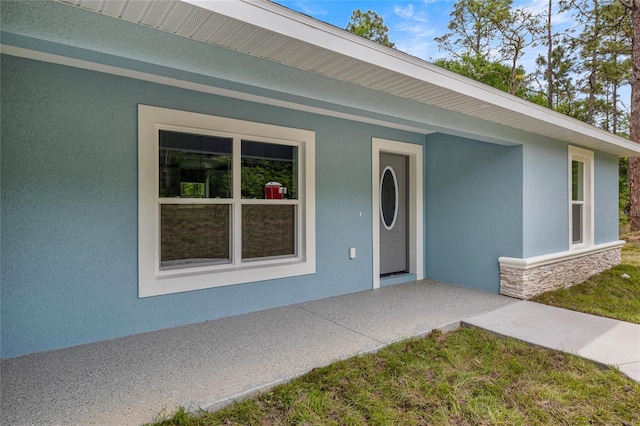 doorway to property featuring stucco siding