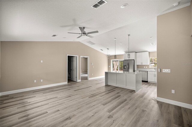 unfurnished living room featuring lofted ceiling, ceiling fan, baseboards, light wood-style flooring, and a textured ceiling